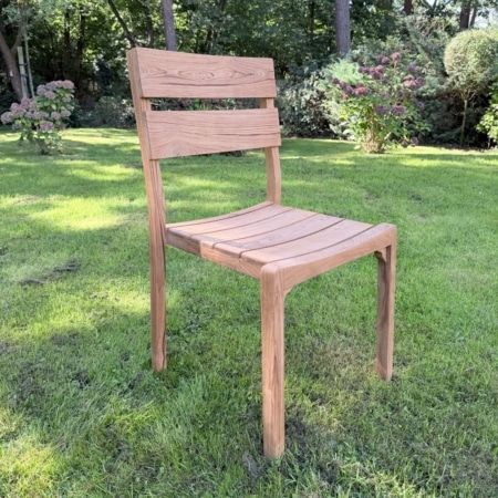 Teakhouten stapelstoel Flores met gebogen lattenzitting in de tuin